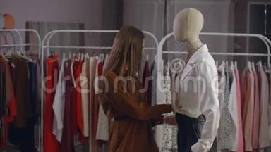 一个年轻的黑发女人看着一家穿着人体模特的服装店。 超市里的服装店。 品牌服装